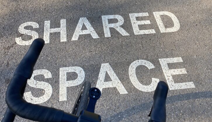 Bike overlooking sign indicating the path is a shared space for pedestrians and cyclists